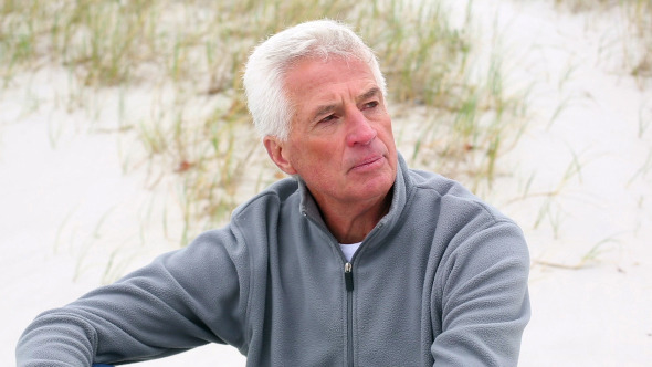 Retired White Haired Man Relaxing On The Beach