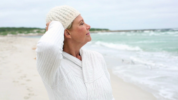 Retired Woman Standing On The Beach Looking Out