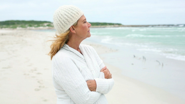 Retired Woman On The Beach Looking Out To Sea