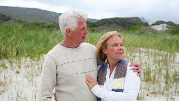 Smiling Retired Couple Standing On The Beach