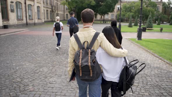 Hugging Couple of Students Walking Through Park