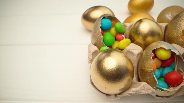 Golden Decorative Easter Eggs Filled with Colorful Candies on Wooden Table Close Up