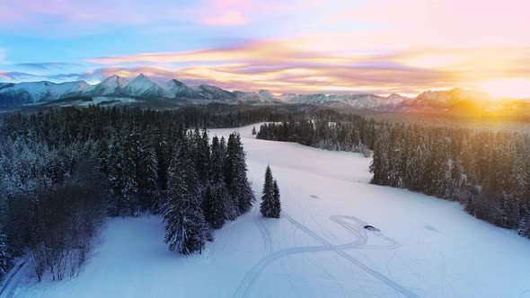 Snow capped mountains in the winter, aerial view. Winter mountain landscape and colorful sunset sky.