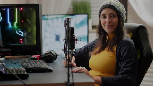 Woman Looking at Camera Sitting in Front of RGB Powerful Computer alt