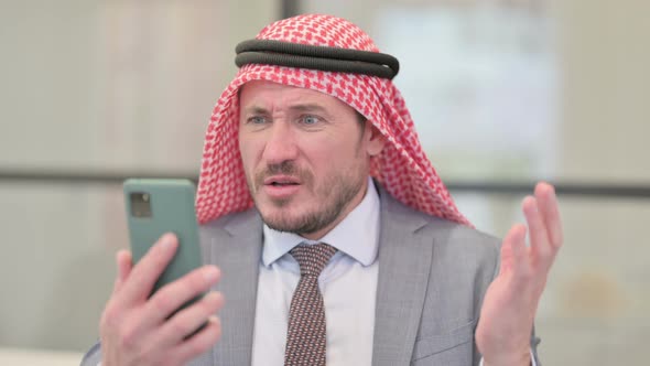 Portrait of Middle Aged Arab Businessman Reacting to Loss on Smartphone alt