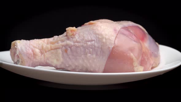 chicken leg or thigh with shin lies on white plate and rotates on turntable alt