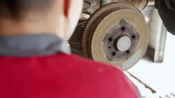a Worker Hits an Old Rusty Car Brake Drum with a Hammer Tries to Remove It alt