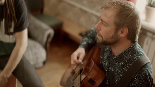 Male Musician Playing Guitar and Singing Near Friend