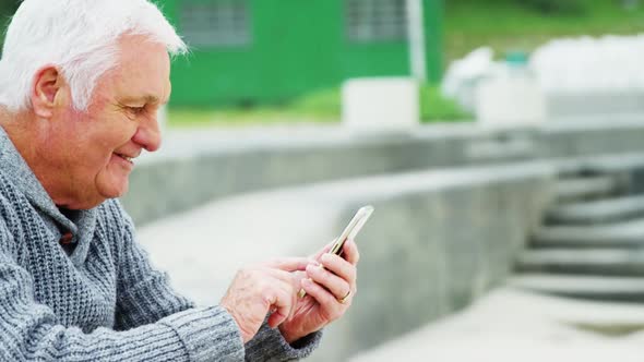 Senior man using mobile phone on beach alt