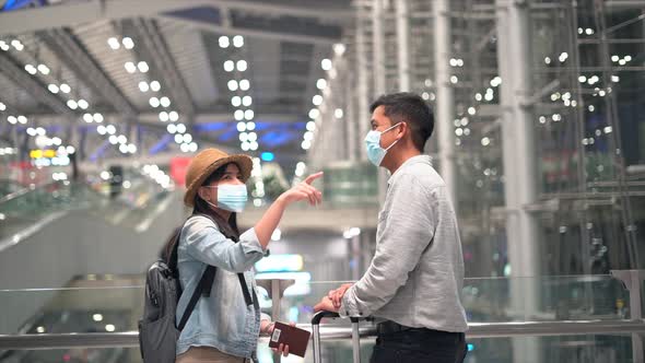 Couple Asian people in airport terminal waiting for  flight boarding.