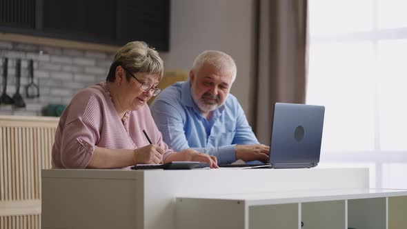 Pair of Retirees are Counting Their Expenses and Income Sitting Together at Kitchen in Apartment Old alt