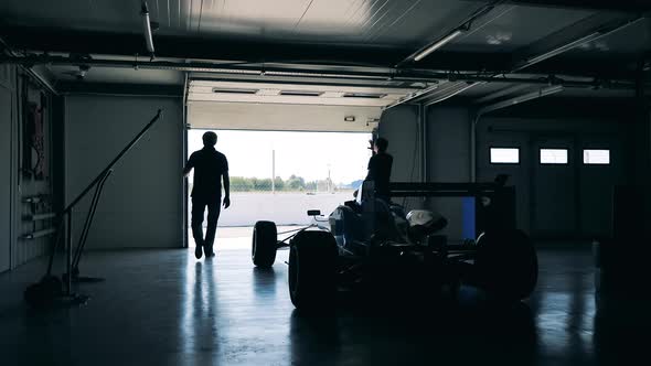 Garage with a Racing Car Inside is Getting Closed By Two Men alt