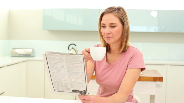 Mature Woman Drinking Coffee Reading Newspaper