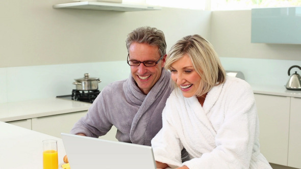 Couple Using Their Laptop At Breakfast Time