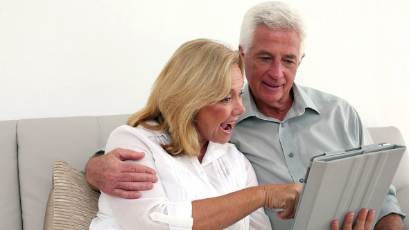 Retired Happy Couple Using Their Tablet