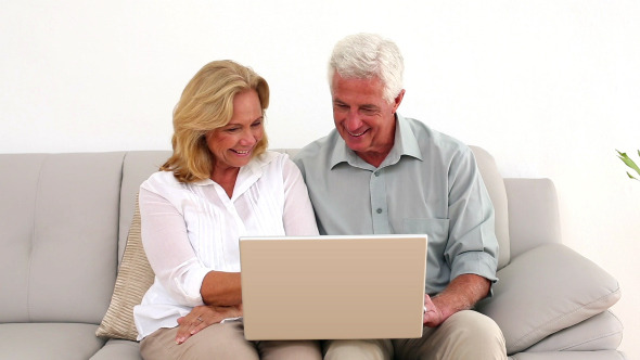Retired Smiling Couple Using Their Laptop