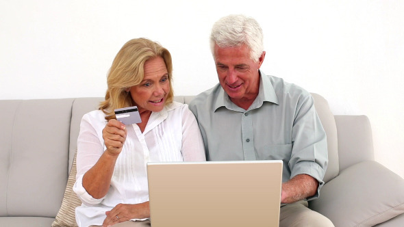 Retired Smiling Couple Using Their Laptop To Shop