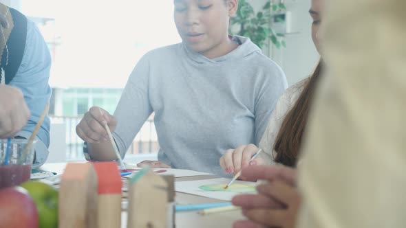 Group of student sitting and studying and learning drawing with teacher together in classroom. alt