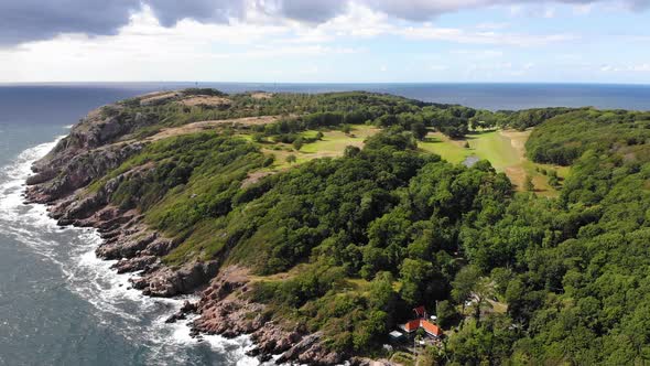 Rugged coastal peninsula of Kullaberg on sunny day with visible horizon, aerial alt