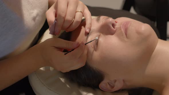 Beauty Therapist Applies a Fixing Product to Eye Lashes of Caucasian Woman for Lamination Procedure