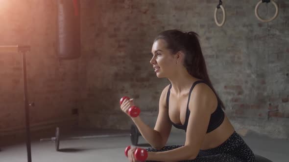 Young Sexy Girl on Fitness Ball at Gym with Red Dumbbells