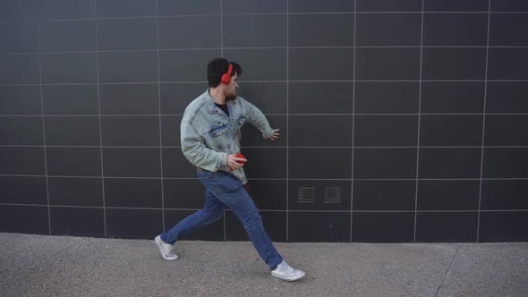 Man dancing in slow motion while walking down the street, listening to music through a telephone and alt