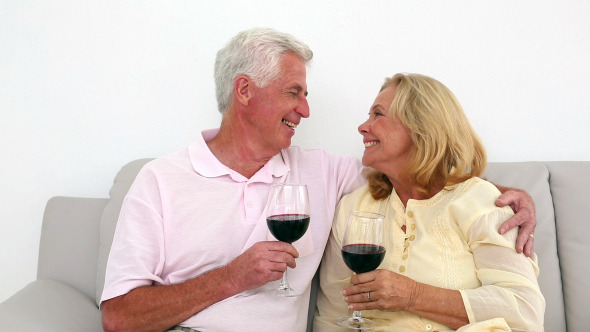 Retired Couple Drinking Red Wine On The Couch