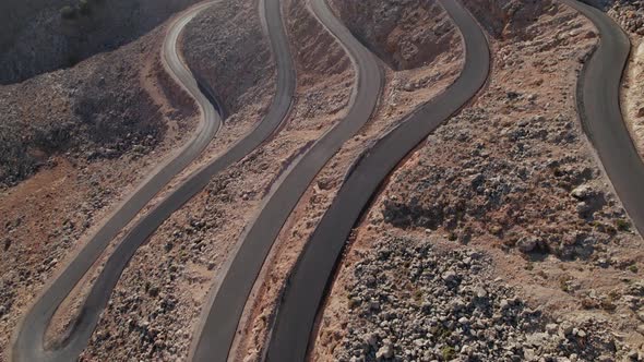 Aerial drone 4K footage of a curved rocky road. Motorway through mountains next to a precipice alt