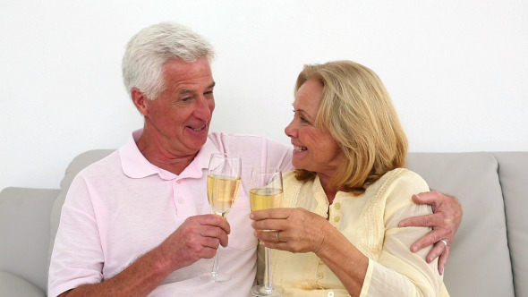 Retired Couple Drinking White Wine On The Couch