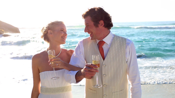 Newlyweds Drinking Champagne On The Beach
