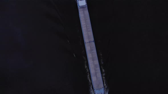 Cargo Barge With Commodities Sailing In River Noord At Dusk In Netherlands. - Aerial Topdown Shot alt