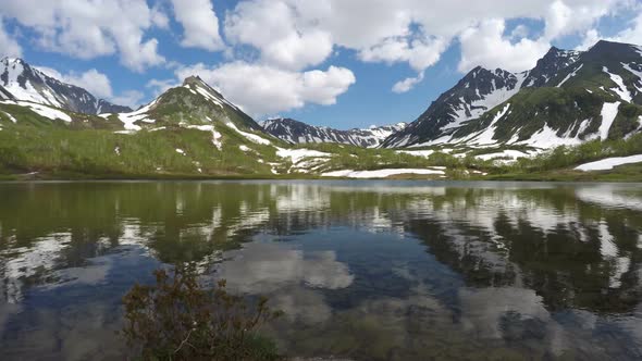 Mountains, mountain lake and clouds drifting across sky on sunny day