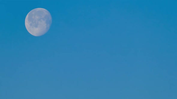 Big round moon in the blue sky during the day, timelapse
