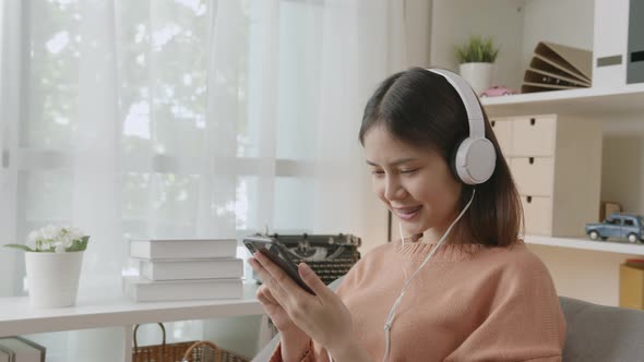 Woman of happy smiling are listening to music from white headphones and using smartphone alt