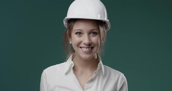 Smiling cheerful businesswoman wearing a safety helmet and looking at camera