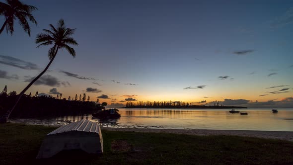 Small boats move with the current on a secret bay, Isle of Pines. Day to night timelapse. alt
