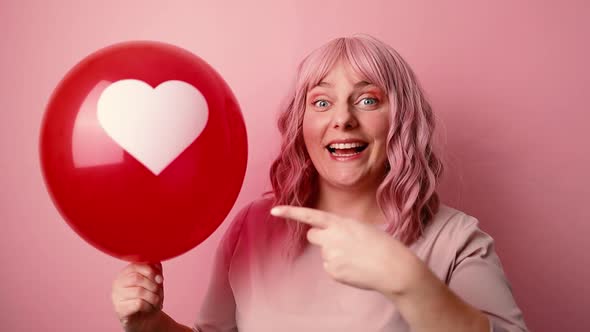 Young Pretty Caucasian Woman Smiling Holding Red Balloon Shaped Heart Isolated on Pink Background