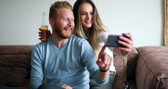 Young Couple in Apartment Looking at Smart Phone and Smiling