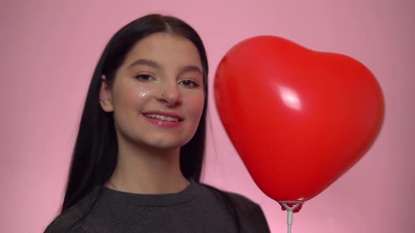 Smiling Woman with Red Heart Balloon Looking at Camera