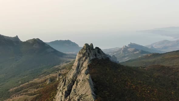 Aerial Slow Motion Footage of a Rocky Mountain Range Covered in Autumn Forest alt