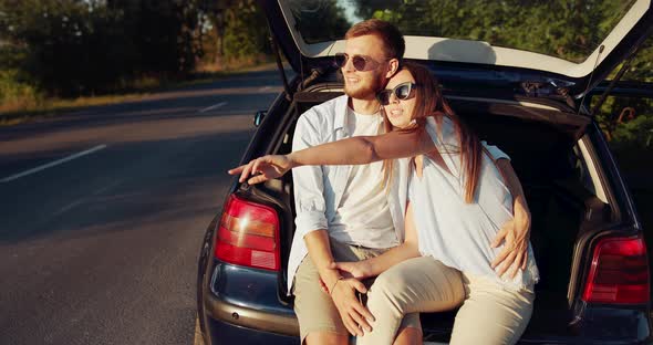 Happy Couple Sitting in Car on Sunset