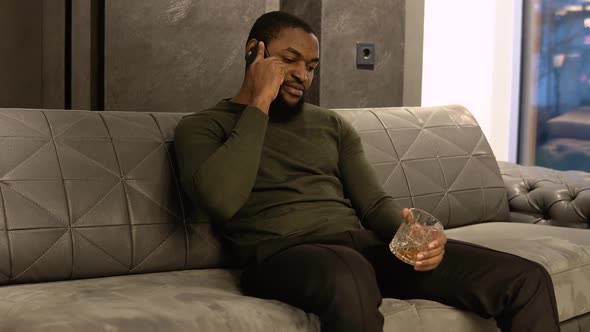 A Young Elegant Bearded Man in a Classic Olive Green Suit Is Sitting on a Sofa in a Showroom or alt