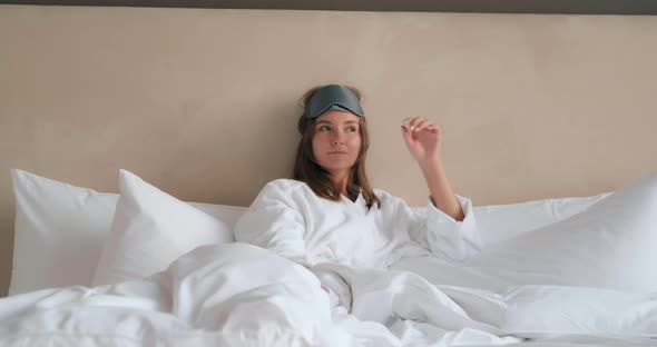 Woman with Sleep Mask and Pajama Lies on Comfortable Bed