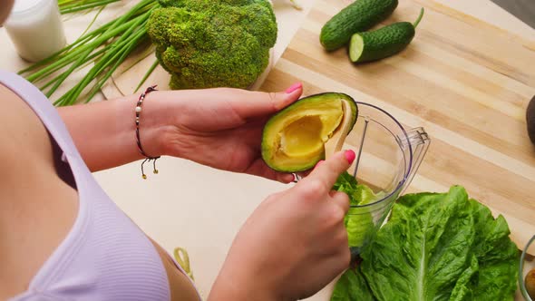 Woman Putting Avocado with Wood Spoon Into Blender Closeup Cooking Green Detox Smoothie in the alt