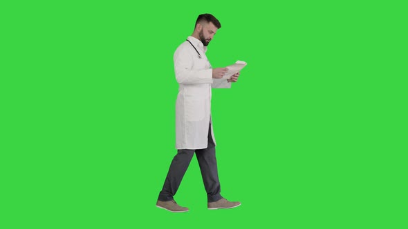 Male Doctor Walking and Looking at Cardiogram on a Green Screen, Chroma Key. alt