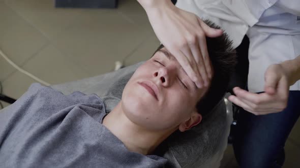 Beautician's Hands Applies the Cream on Man's Face Skin with Massage Movements alt