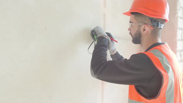 Male Contractor Measuring and Making Marks on Wall