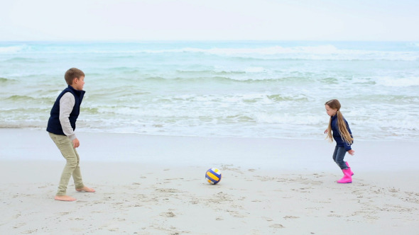 Siblings Playing Football On The Beach