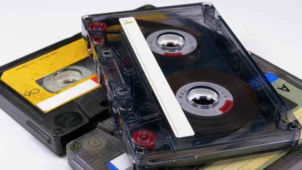 Three Vintage Audio Cassettes Rotate on White Background alt