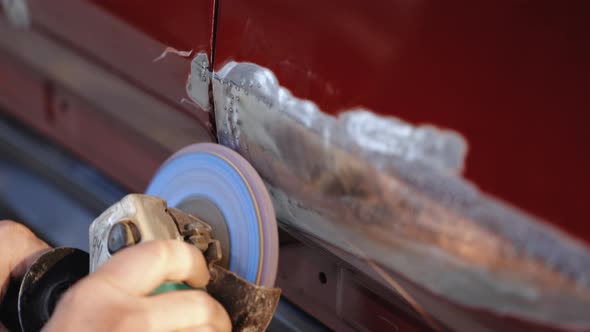 Professional Auto Workshop Worker Grinds Dented Door of Car